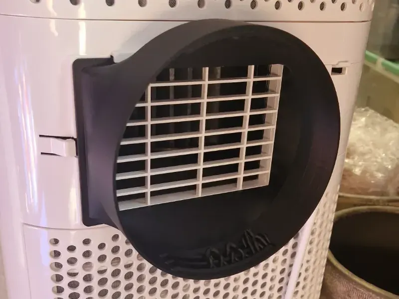 Adaptateur noir à grille, fixé à l’arrière d’un climatiseur mobile blanc